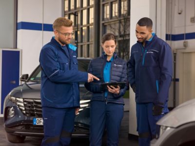 Des employés dans un atelier travaillant ensemble sur une tablette.